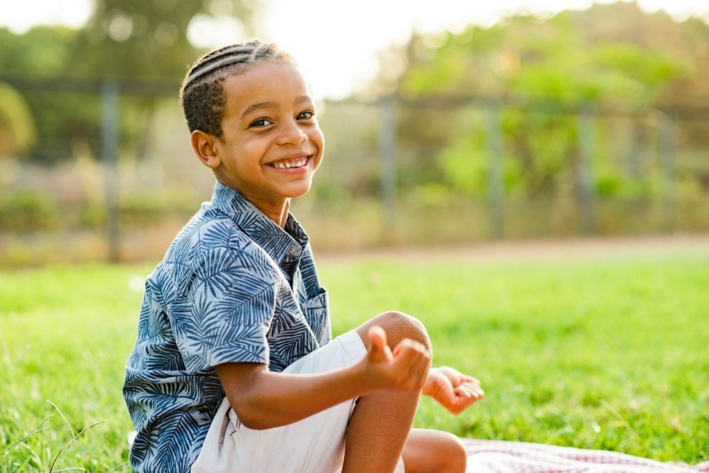 Delighted black kid smiling at camera during picnic