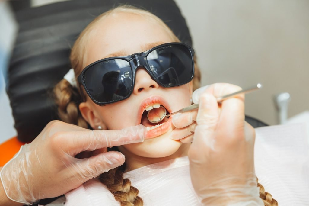 the dentist makes an examination of the teeth of a little girl. pediatric dentistry