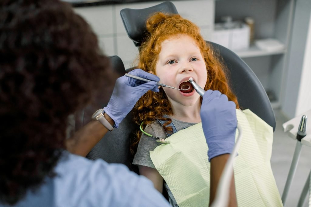 Red haired girl during the dental procedure at the modern children's dental clinic